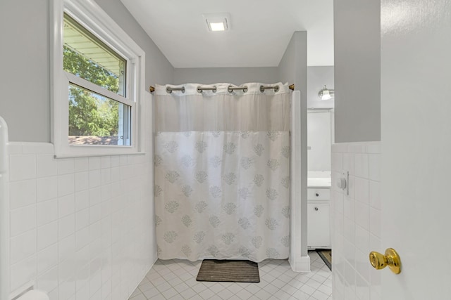 bathroom featuring vanity, tile walls, tile patterned floors, and walk in shower