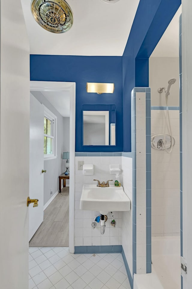 bathroom featuring tile patterned flooring, sink, tile walls, and a tile shower