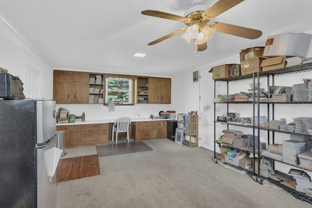 kitchen featuring stainless steel refrigerator, ceiling fan, built in desk, ornamental molding, and light carpet