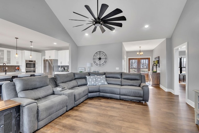 living room with hardwood / wood-style flooring, a notable chandelier, high vaulted ceiling, and french doors