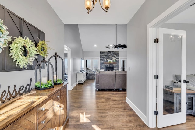 corridor featuring a notable chandelier, dark wood-type flooring, and vaulted ceiling