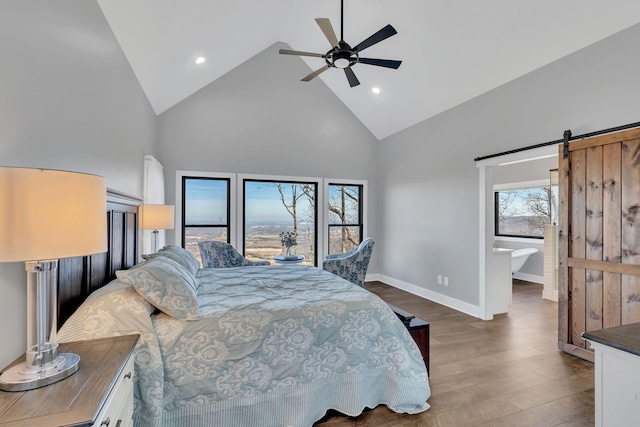 bedroom with ensuite bathroom, high vaulted ceiling, dark hardwood / wood-style flooring, ceiling fan, and a barn door