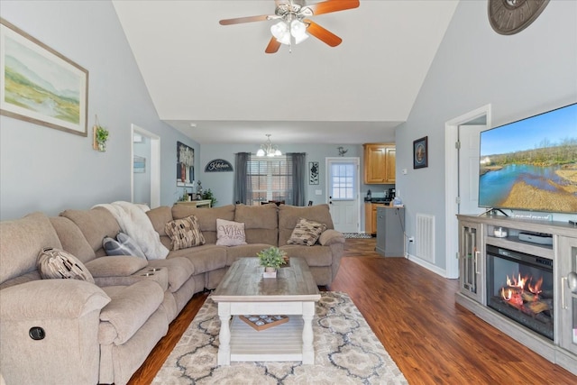 living room with ceiling fan with notable chandelier, high vaulted ceiling, and dark hardwood / wood-style floors