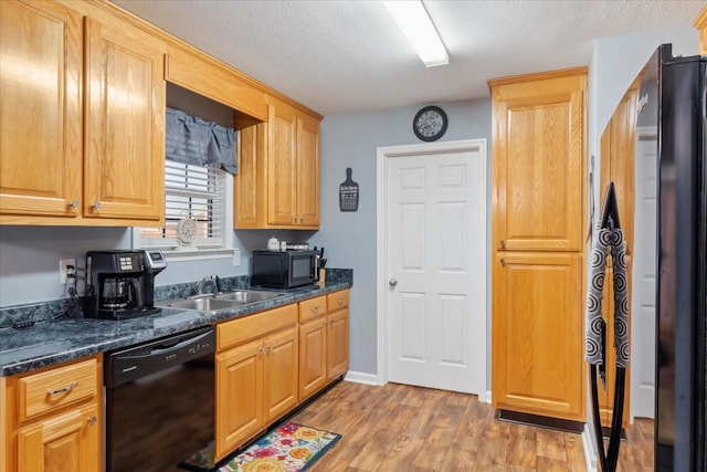 kitchen featuring sink, black appliances, light hardwood / wood-style floors, and a textured ceiling