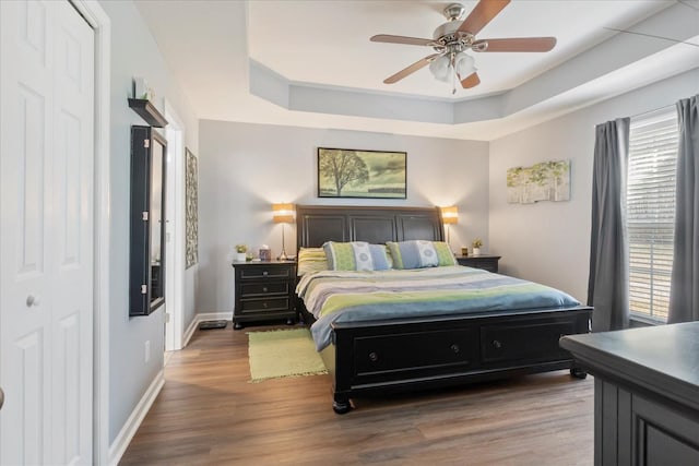 bedroom featuring a tray ceiling, wood-type flooring, and ceiling fan