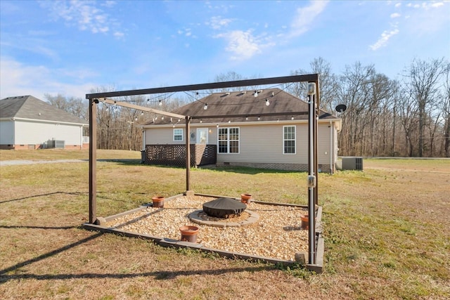 rear view of house featuring cooling unit, a lawn, and an outdoor fire pit