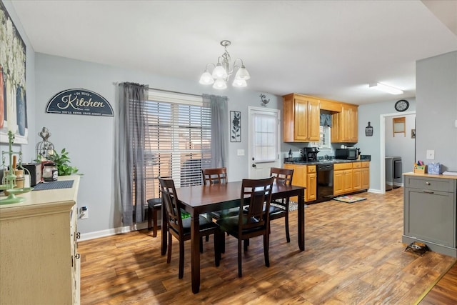 dining room with an inviting chandelier, washer / clothes dryer, and light hardwood / wood-style flooring