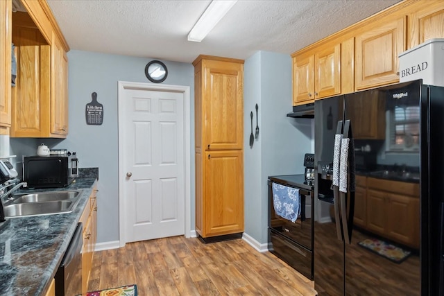 kitchen featuring sink, a textured ceiling, dark stone counters, light hardwood / wood-style floors, and black appliances