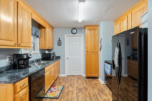 kitchen featuring sink, dark stone counters, black appliances, a textured ceiling, and light hardwood / wood-style flooring