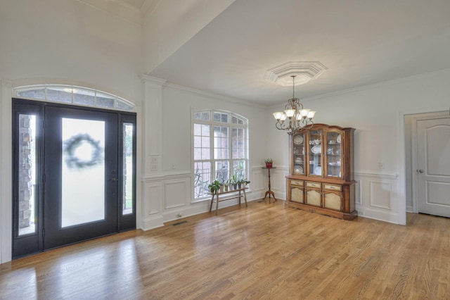 foyer featuring ornamental molding, light hardwood / wood-style flooring, and a notable chandelier