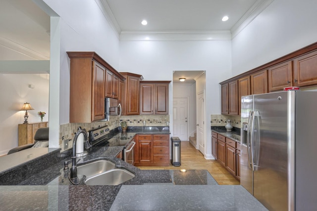 kitchen with sink, crown molding, appliances with stainless steel finishes, tasteful backsplash, and light wood-type flooring