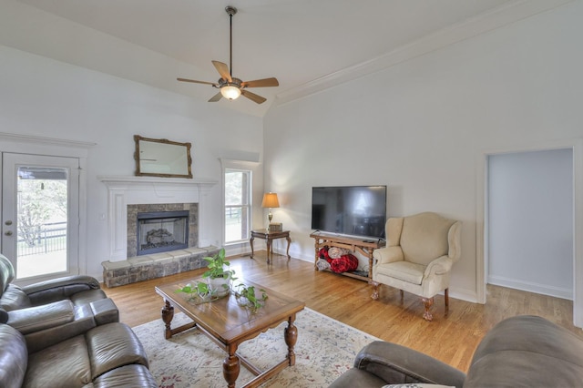 living room with wood-type flooring, plenty of natural light, a stone fireplace, and ceiling fan