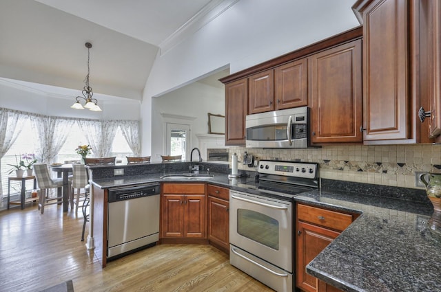 kitchen with vaulted ceiling, decorative light fixtures, sink, backsplash, and stainless steel appliances