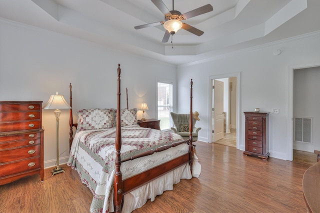 bedroom featuring ceiling fan, a tray ceiling, and light hardwood / wood-style floors