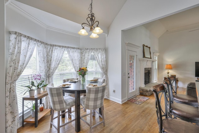 dining space with ornamental molding, light hardwood / wood-style flooring, high vaulted ceiling, and a chandelier