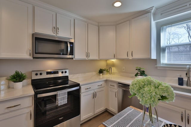 kitchen with light stone counters, white cabinets, and appliances with stainless steel finishes