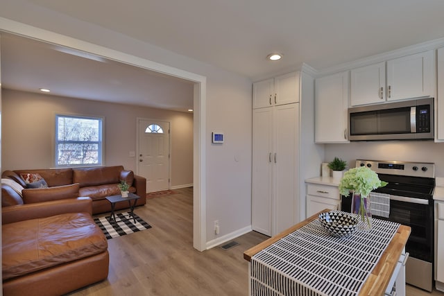 kitchen featuring white cabinetry, appliances with stainless steel finishes, wood counters, and light wood-type flooring