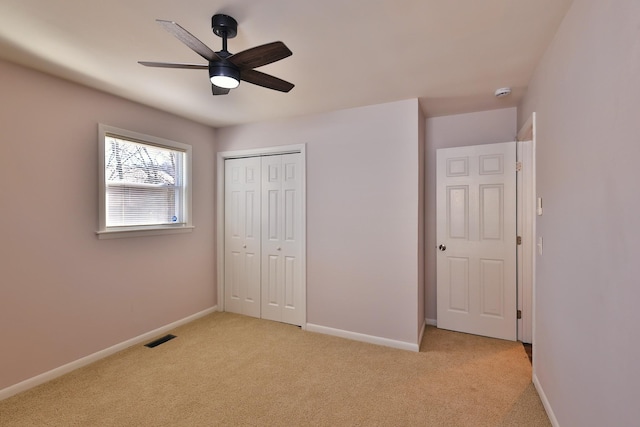 unfurnished bedroom with light colored carpet, a closet, and ceiling fan