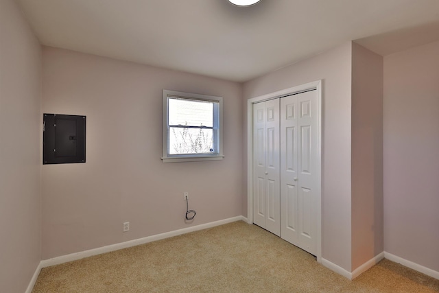 unfurnished bedroom featuring a closet, electric panel, and light carpet