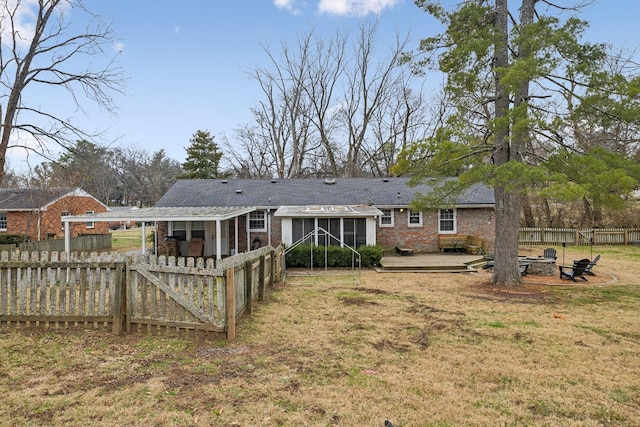 back of property with a sunroom, a patio area, and a lawn