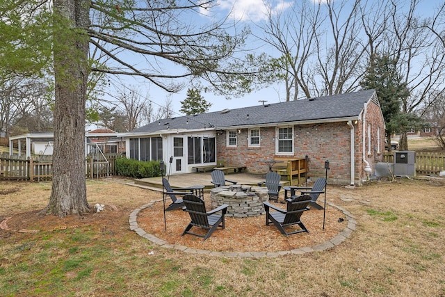 rear view of house with a yard, a sunroom, a patio, and an outdoor fire pit