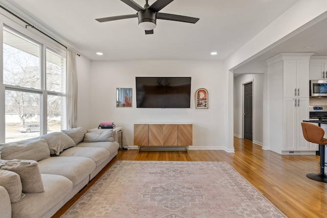 living room featuring ceiling fan, plenty of natural light, and light hardwood / wood-style floors