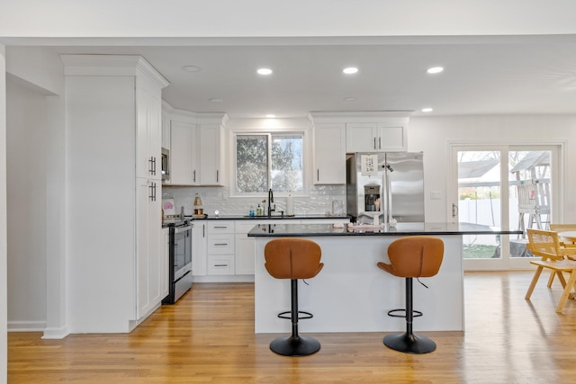 kitchen featuring stainless steel appliances, a kitchen bar, a kitchen island, and white cabinets