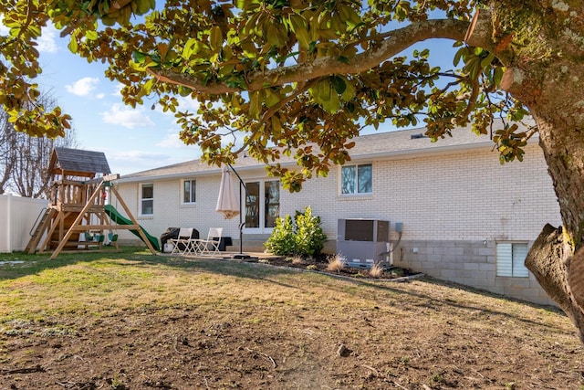 rear view of property featuring cooling unit, a yard, and a playground