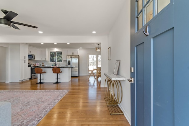 entryway with ceiling fan, sink, and light hardwood / wood-style floors