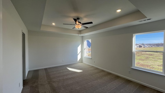 carpeted spare room featuring ceiling fan and a raised ceiling