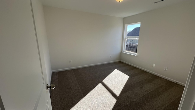 spare room featuring dark colored carpet