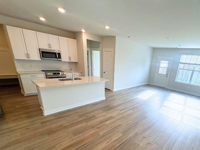 kitchen featuring white cabinetry, an island with sink, sink, decorative backsplash, and stainless steel appliances