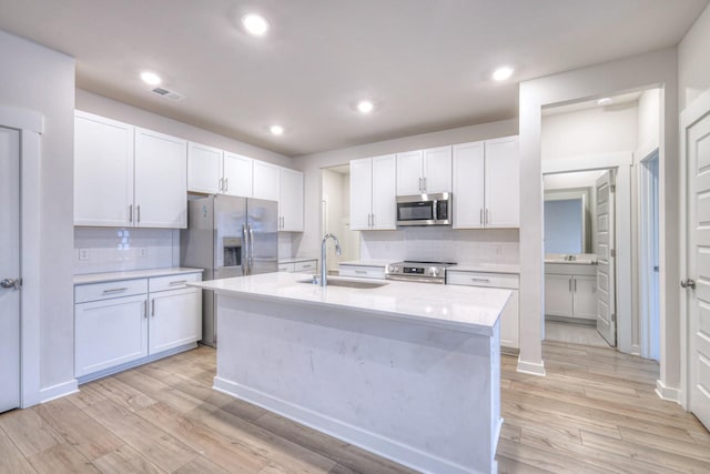 kitchen featuring sink, light hardwood / wood-style flooring, stainless steel appliances, an island with sink, and white cabinets