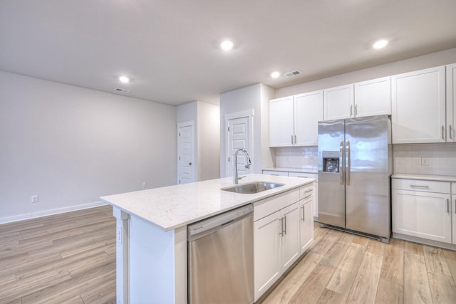 kitchen with stainless steel appliances, white cabinetry, sink, and an island with sink