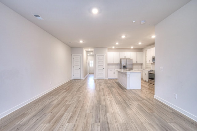 kitchen with white cabinetry, light hardwood / wood-style flooring, stainless steel appliances, and a center island with sink