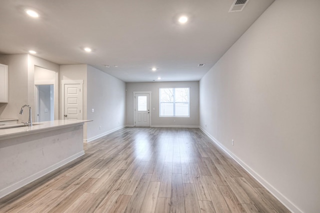 unfurnished living room with sink and light wood-type flooring