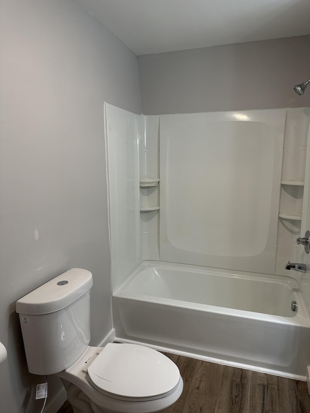 bathroom with hardwood / wood-style flooring, shower / bath combination, and toilet