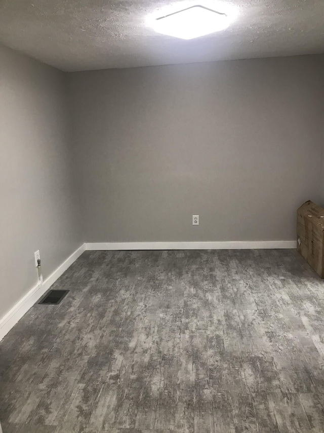 spare room with dark hardwood / wood-style floors and a textured ceiling