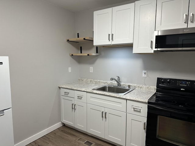 kitchen featuring black electric range oven, sink, white cabinetry, white refrigerator, and dark hardwood / wood-style flooring