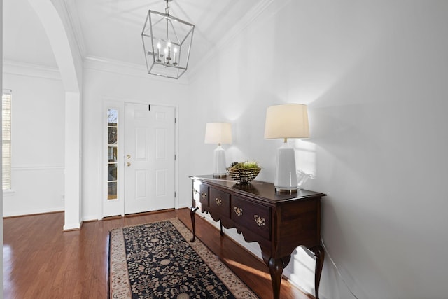 foyer entrance featuring dark hardwood / wood-style flooring, a notable chandelier, and crown molding