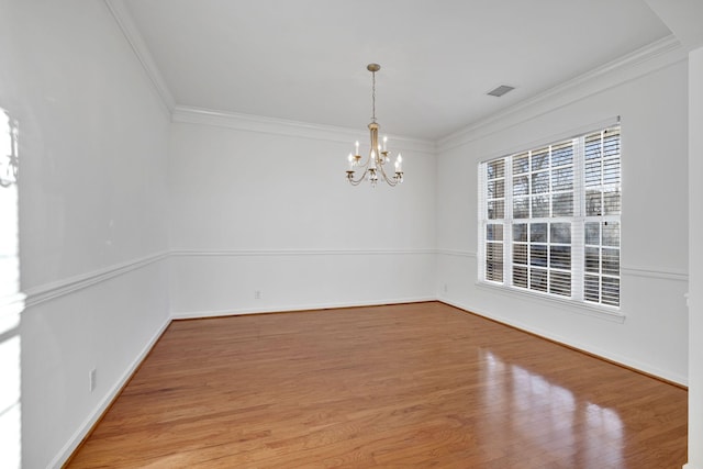 empty room with crown molding, hardwood / wood-style floors, and a chandelier