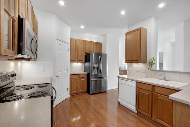 kitchen featuring stainless steel appliances, light hardwood / wood-style floors, sink, and decorative backsplash