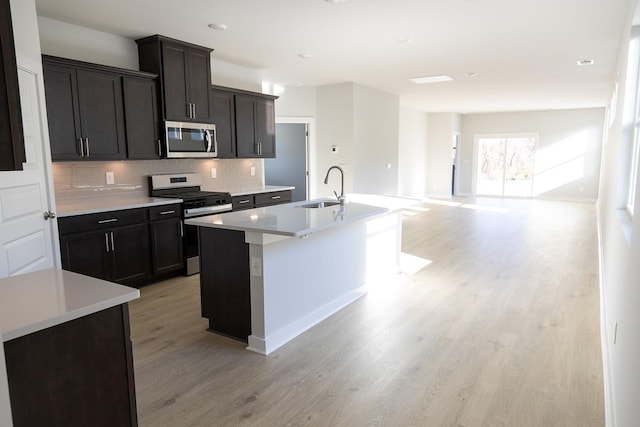 kitchen featuring stainless steel appliances, sink, a center island with sink, and backsplash