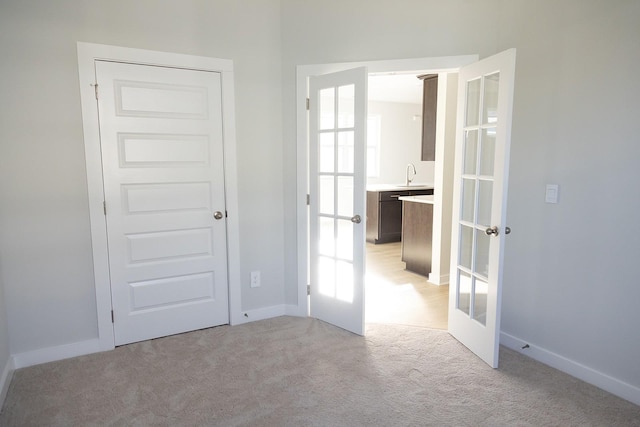 carpeted empty room with sink and french doors