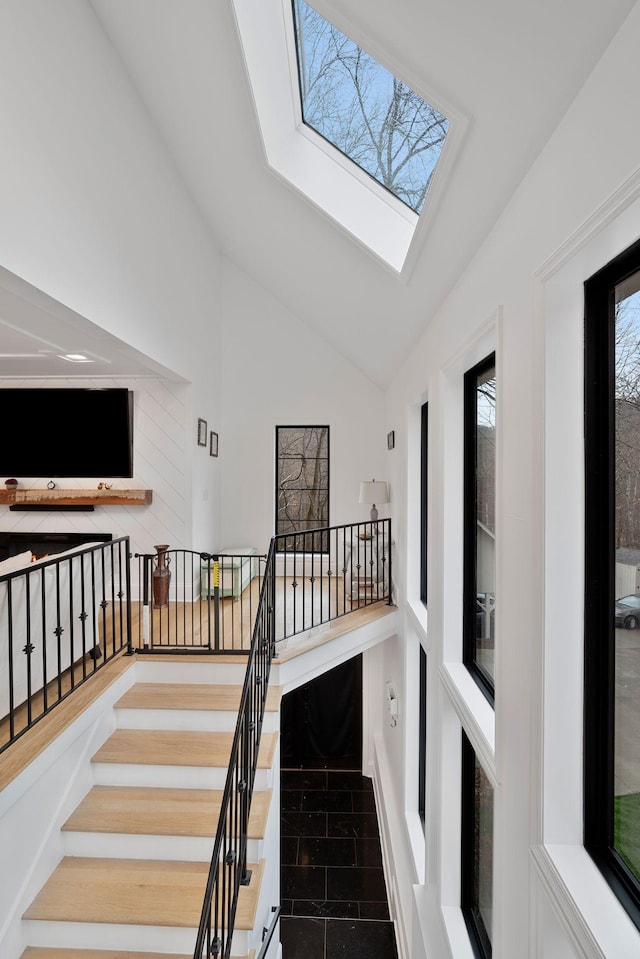 stairway featuring high vaulted ceiling and a skylight