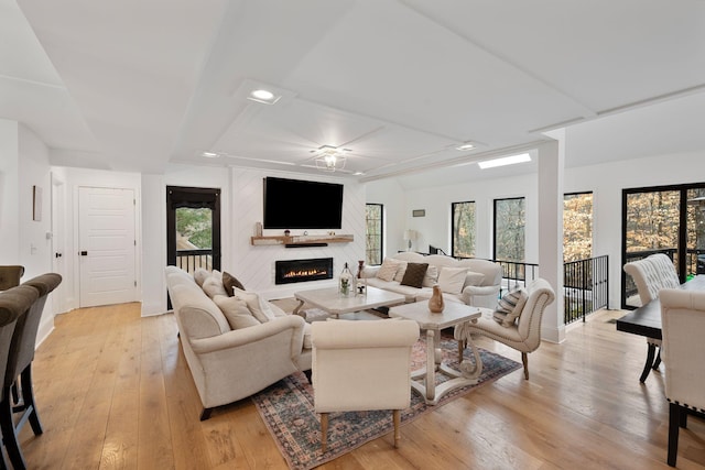 living room featuring plenty of natural light, a large fireplace, and light wood-type flooring