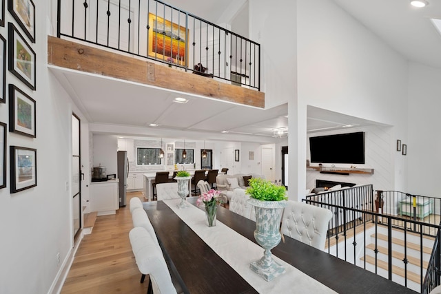 dining space with a towering ceiling and light hardwood / wood-style flooring