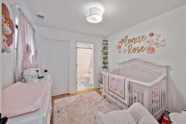 bedroom featuring ensuite bath, light hardwood / wood-style floors, and a nursery area