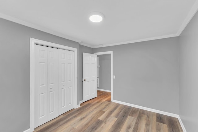 unfurnished bedroom with hardwood / wood-style flooring, ornamental molding, and a closet