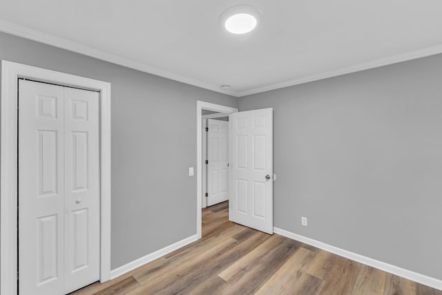 unfurnished bedroom with ornamental molding, hardwood / wood-style floors, and a closet